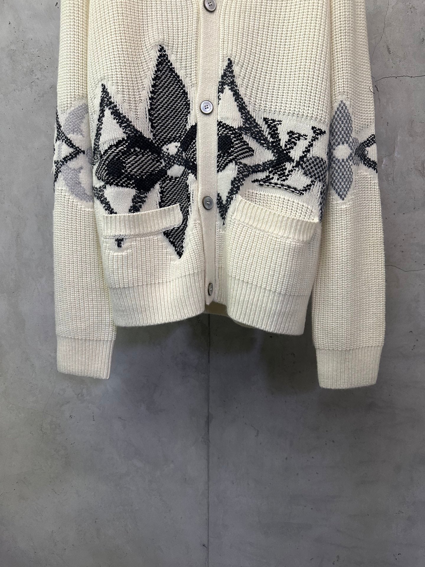 Cream knit cardigan with black patterned front and matching pocket on the left side