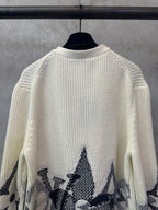 Cream knit sweater with black star-like motifs on the sleeves and lower hem