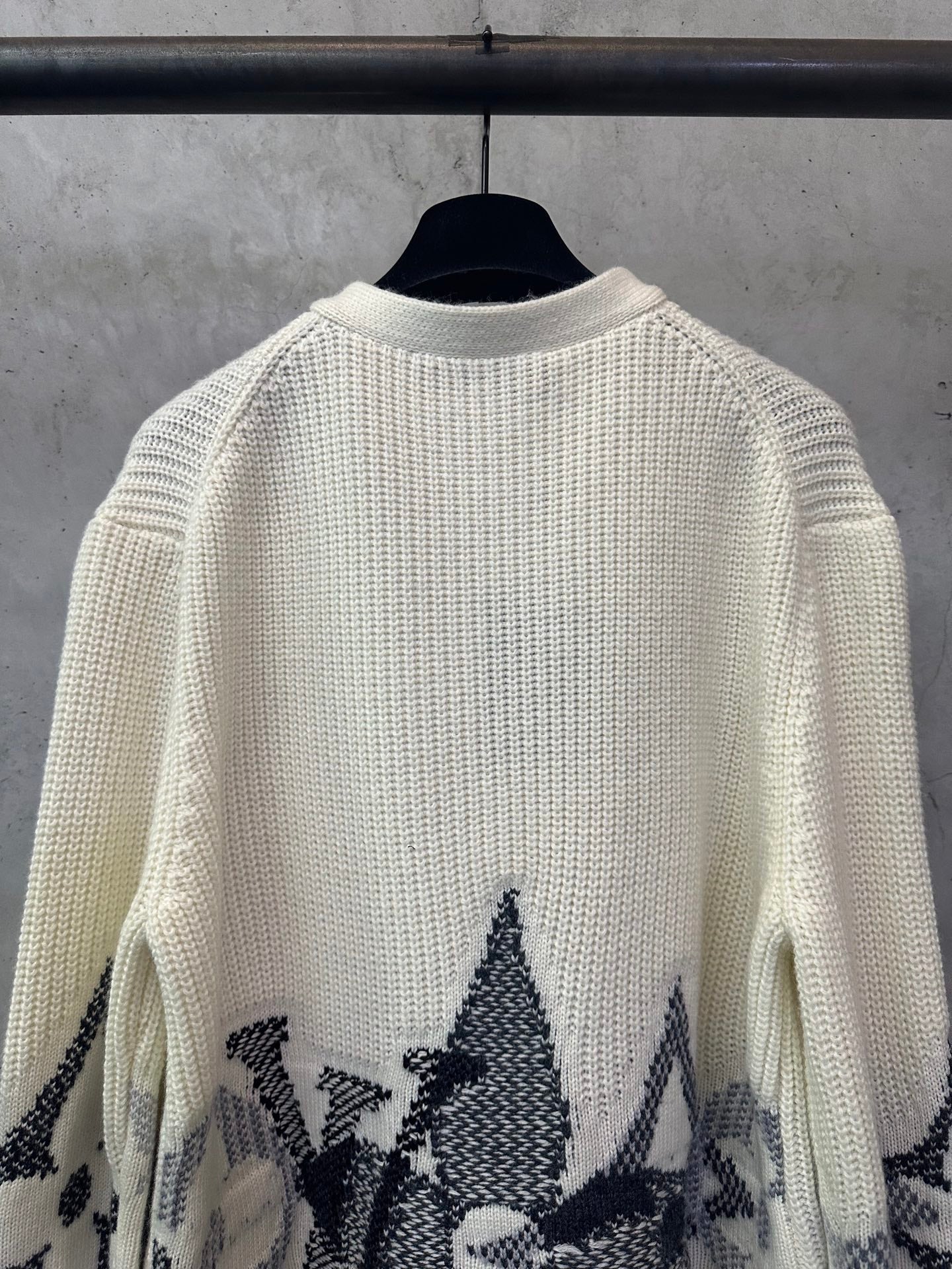 Cream knit sweater with black star-like motifs on the sleeves and lower hem