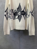 Cream knit sweater with black floral and star-like motifs on the front