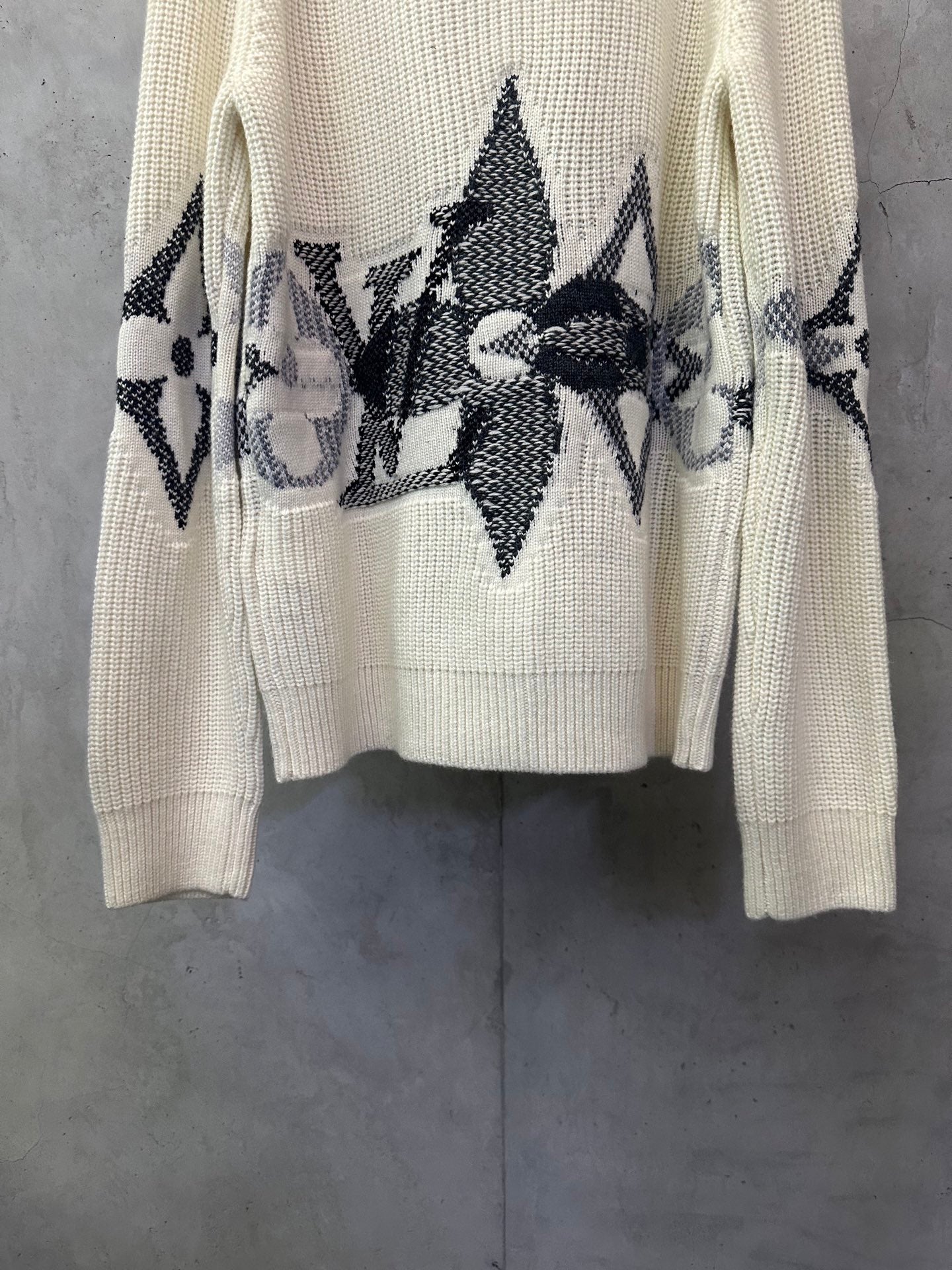 Cream knit sweater with black floral and star-like motifs on the front