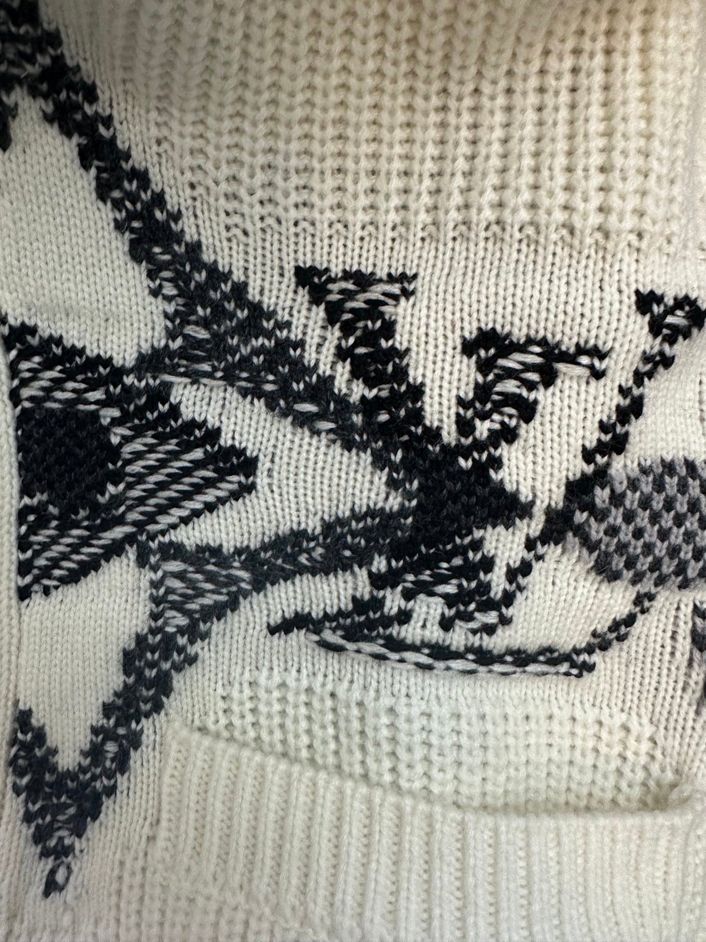 Close-up of cream knit fabric with black star and cross pattern embroidery