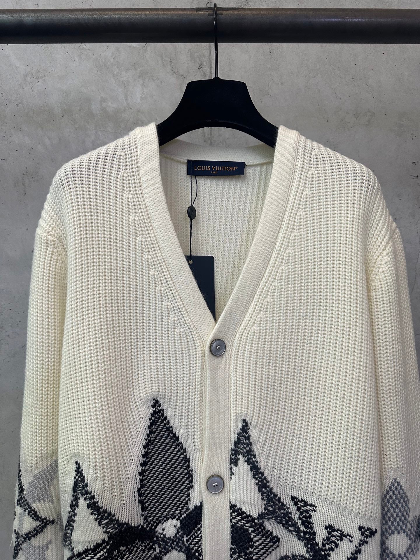 Cream knit cardigan with V-neck and black patterned designs on the front panels