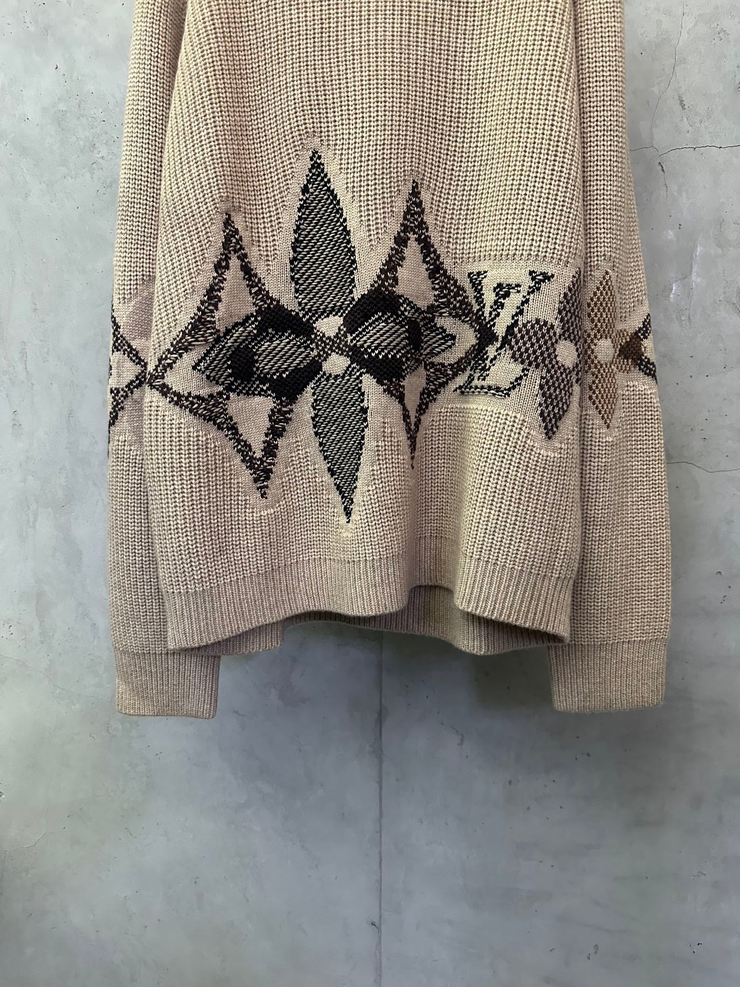 Beige knit sweater with black geometric diamond motif across the chest