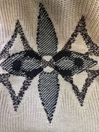 Close-up of beige knit fabric with black geometric diamond motif