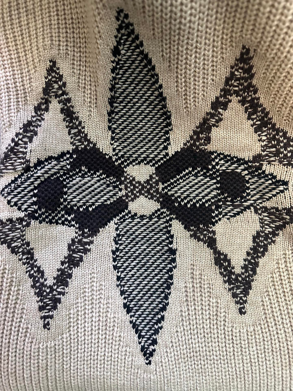 Beige knit sweater close-up with black-and-white geometric star motif