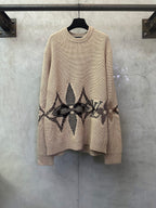 Beige knit sweater with long sleeves and black geometric patterned hem panel