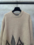 Beige knit sweater with long sleeves and black geometric motif on front lower area