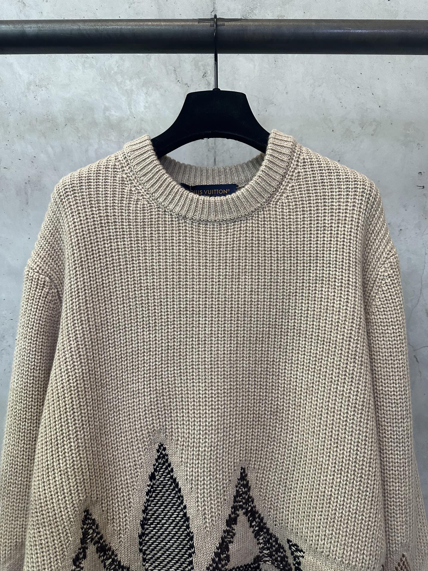 Beige crew-neck knit sweater with black motif near the lower front