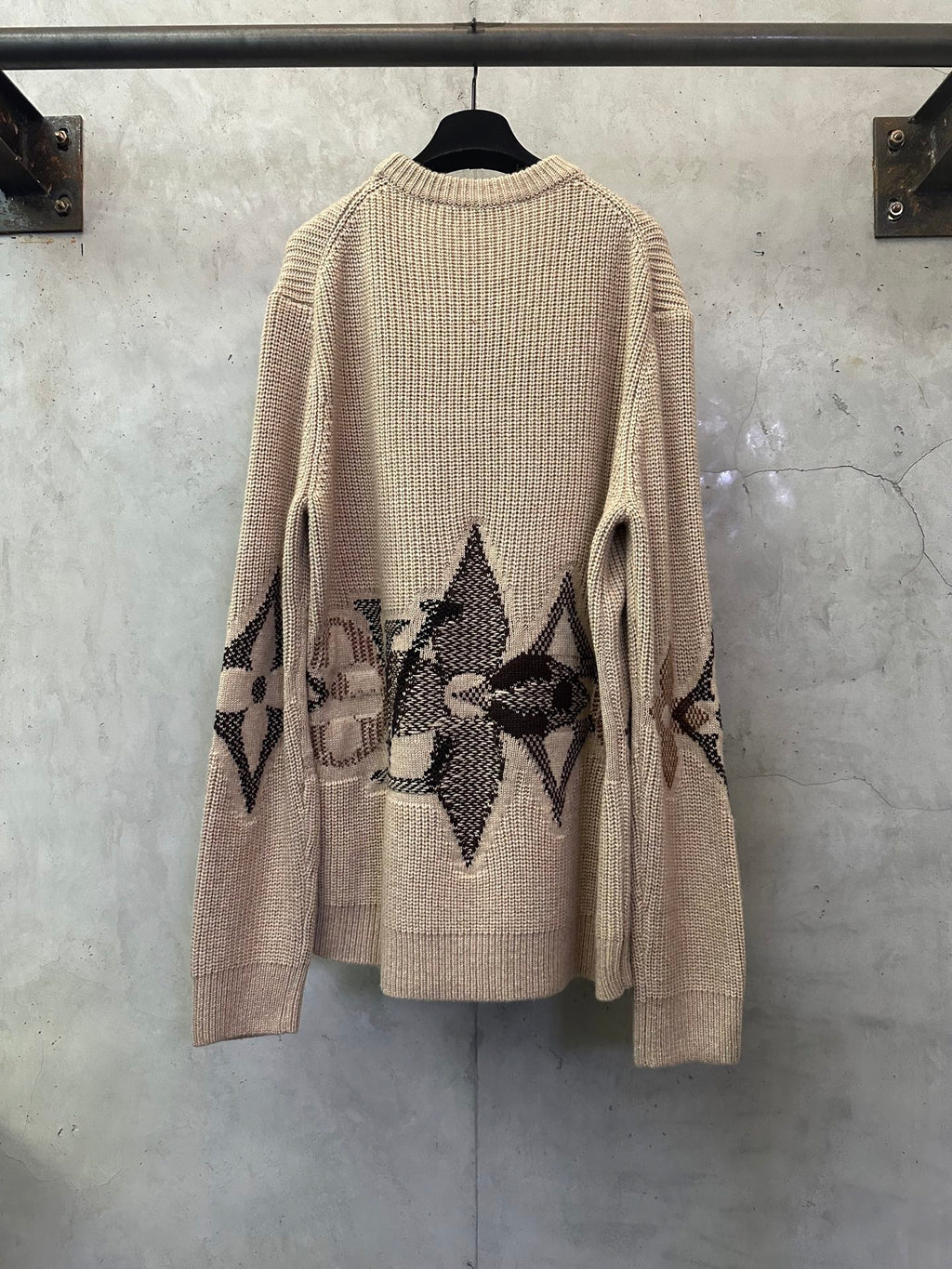 Beige knit long-sleeve sweater with black patterned motif on the sleeves and hem