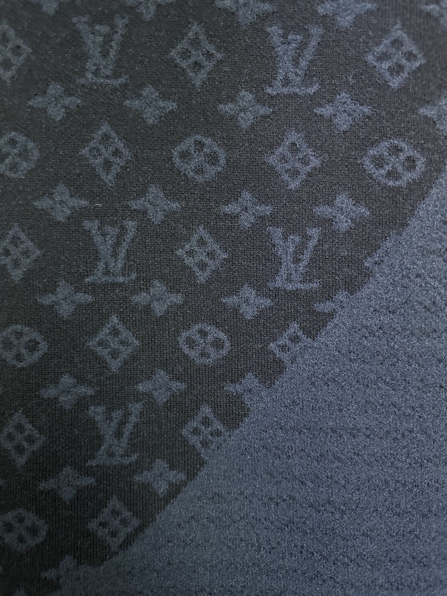 Dark blue knit fabric with repeating monogram pattern