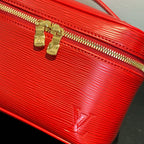 Louis Vuitton red cosmetic bag close-up: gold zipper pulls on textured leather.