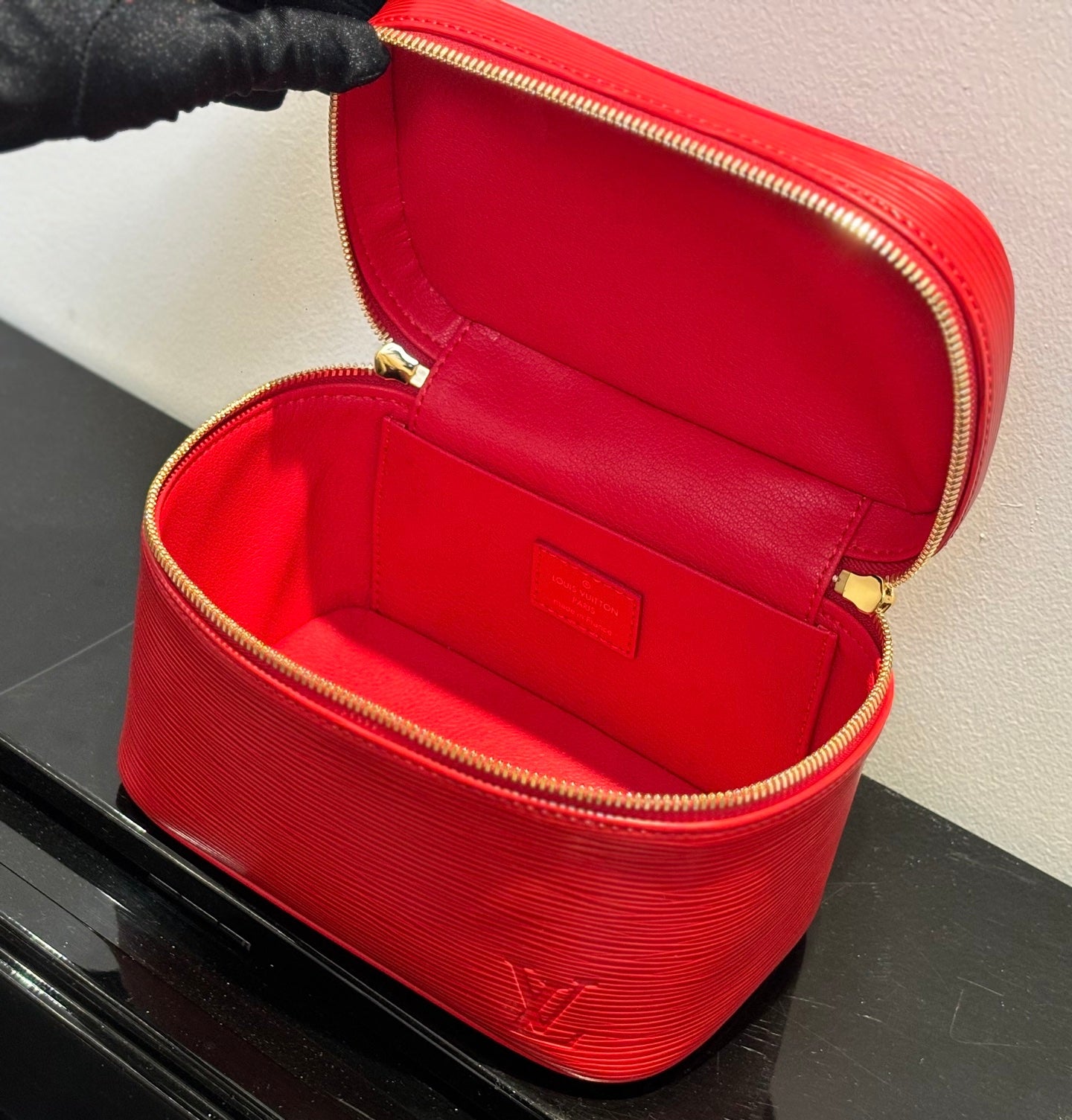 Louis Vuitton red cosmetic bag open to reveal red interior and gold zipper track.