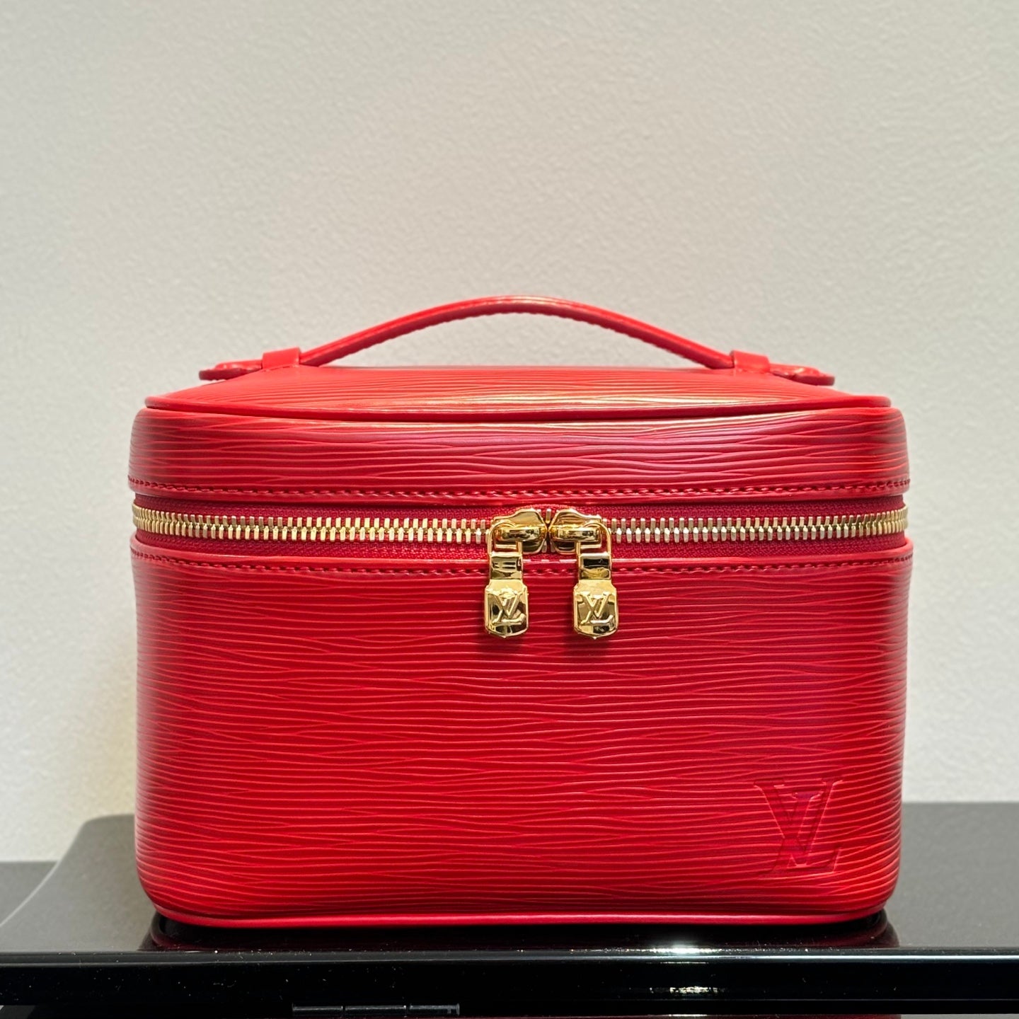 Louis Vuitton red cosmetic bag with gold zipper, top handle, embossed logo.