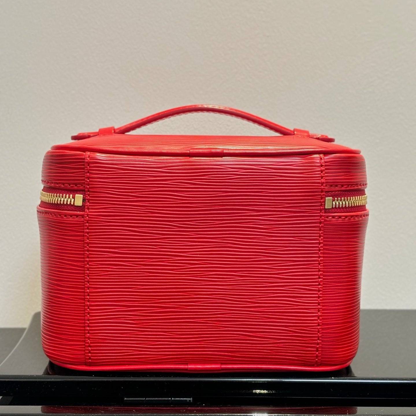 Louis Vuitton red cosmetic bag with top handle and stitched sides, gold zippers.