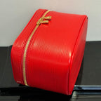 Louis Vuitton red cosmetic bag side view with gold zipper trim and handle.