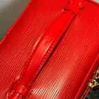 Louis Vuitton red cosmetic bag close-up of leather strap with gold hardware.