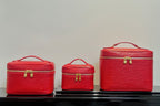 Louis Vuitton red cosmetic bag set: small, medium, and large cases with handles.
