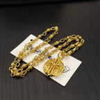 Gold-tone chain necklace with round red enamel crest pendant, layered on cards.