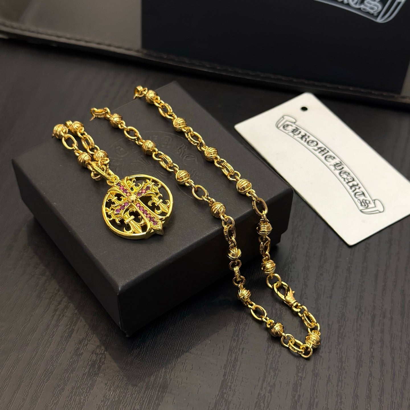 Gold-tone chain necklace with round red enamel crest pendant, close view.