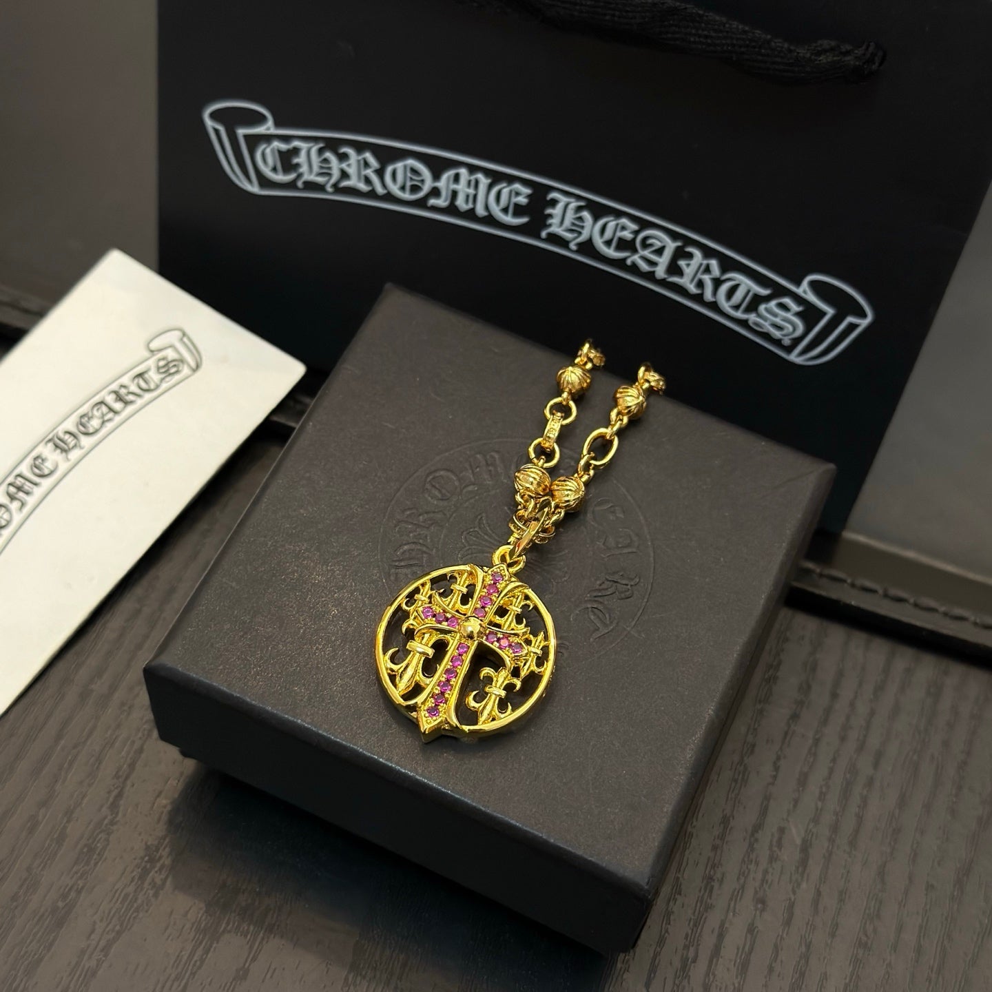 Gold-tone chain necklace with round red crest pendant on display.