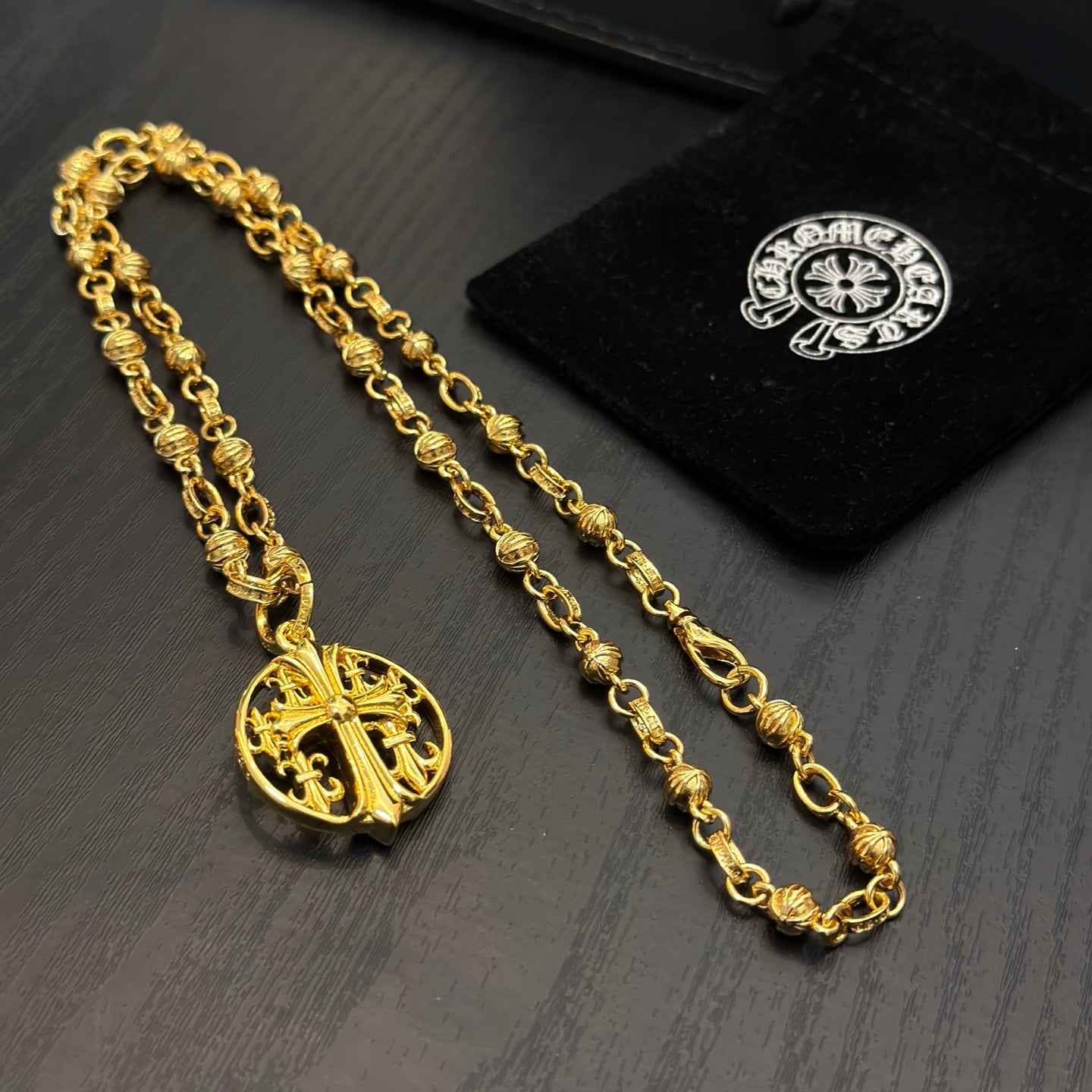 Gold-tone chain necklace with round red enamel crest pendant, shown with tags.