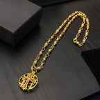 Gold-tone chain necklace with round red enamel crest pendant and linked chain.
