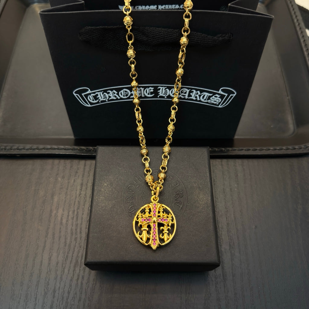 Gold-tone chain necklace with round red enamel crest pendant.