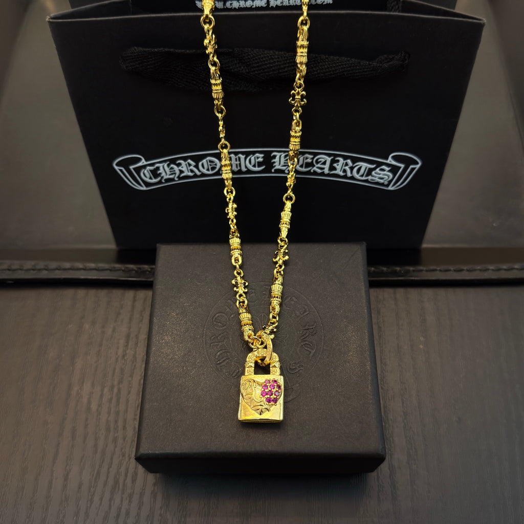 Gold-tone pendant necklace with rectangular charm featuring pink gemstone accents