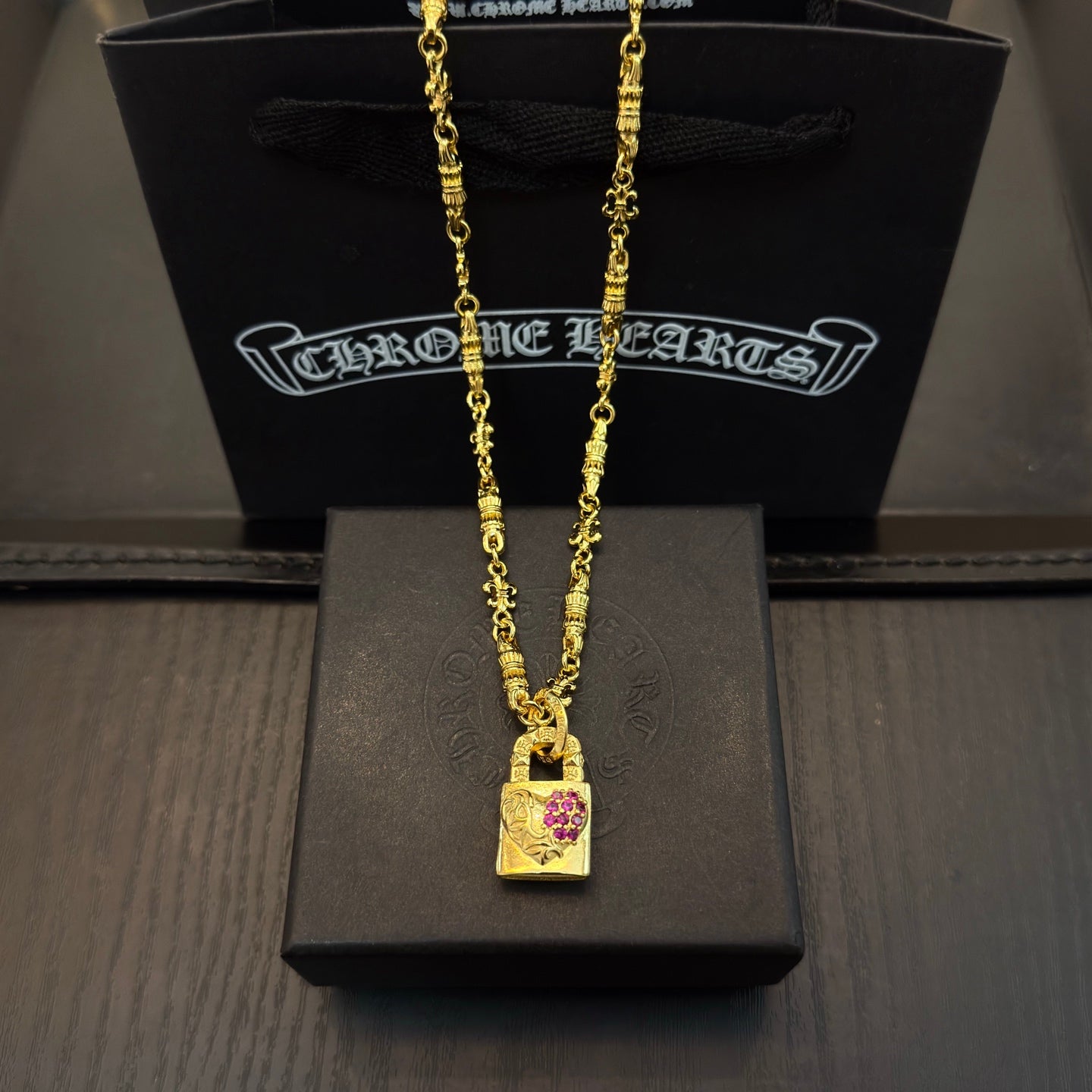 Gold-tone pendant necklace with rectangular charm featuring pink gemstone accents