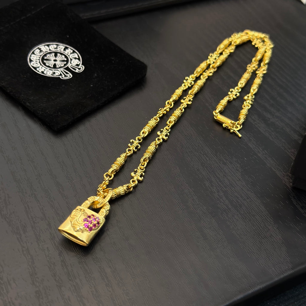 Gold-tone long pendant necklace with pink gemstone charm and clasp hardware