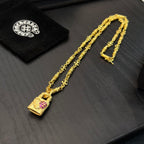Gold-tone long pendant necklace with pink gemstone charm and clasp hardware