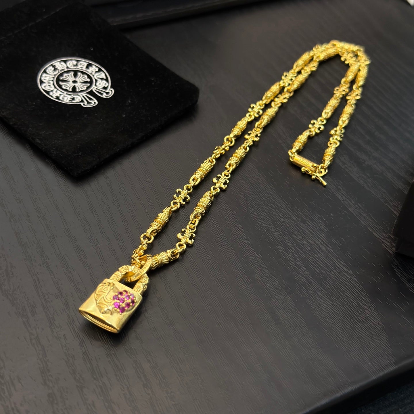 Gold-tone long pendant necklace with pink gemstone charm and clasp hardware