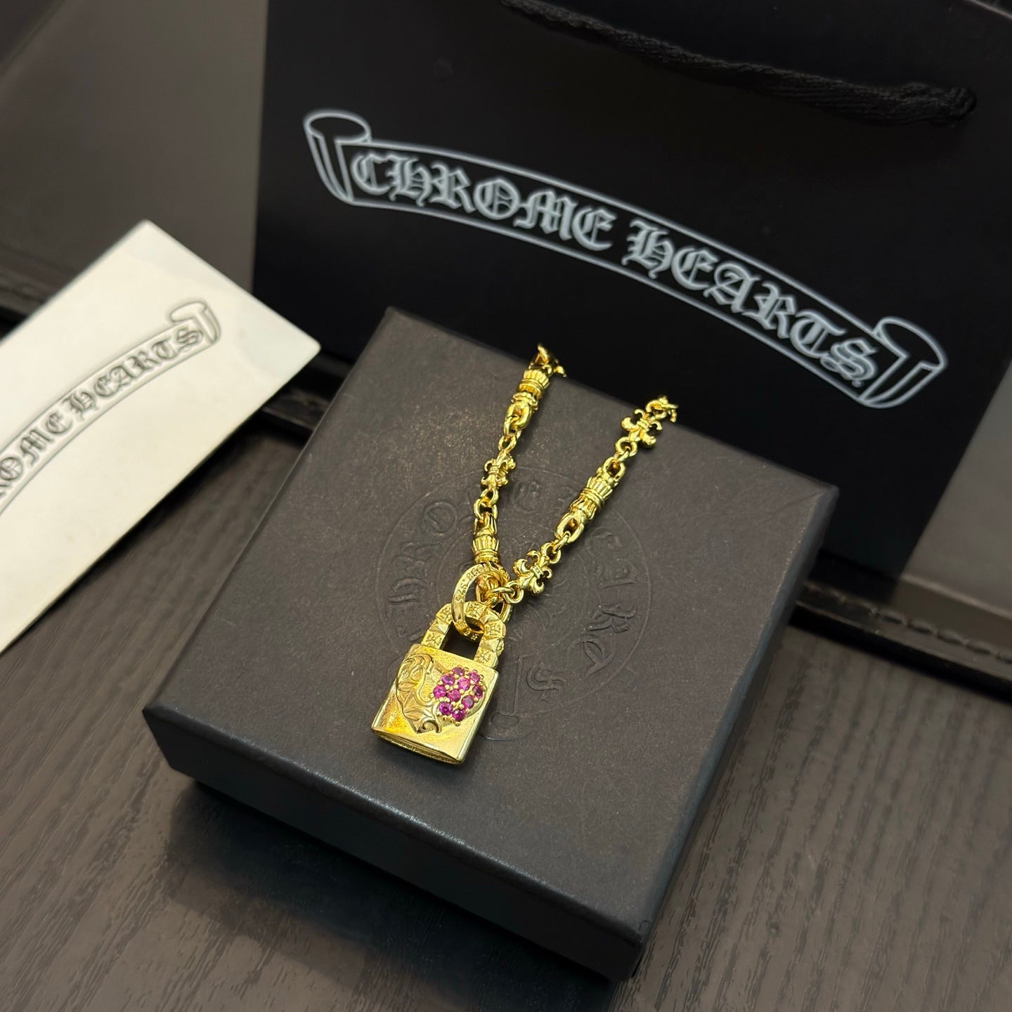 Gold-tone pendant necklace with square charm and pink gemstone center