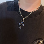 Cross pendant necklace with blue enamel pendant on model’s dark top