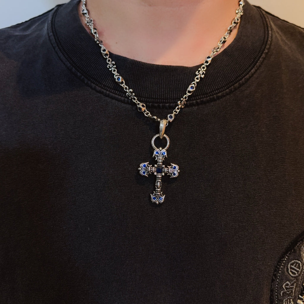 Cross pendant necklace with blue enamel on model’s dark shirt