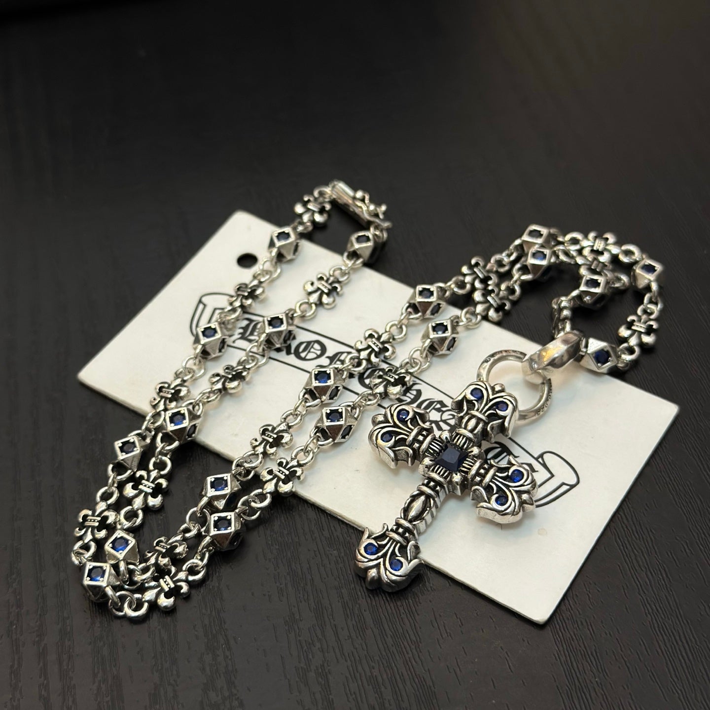 Cross pendant necklace with blue enamel and silver-tone chain on jewelry card