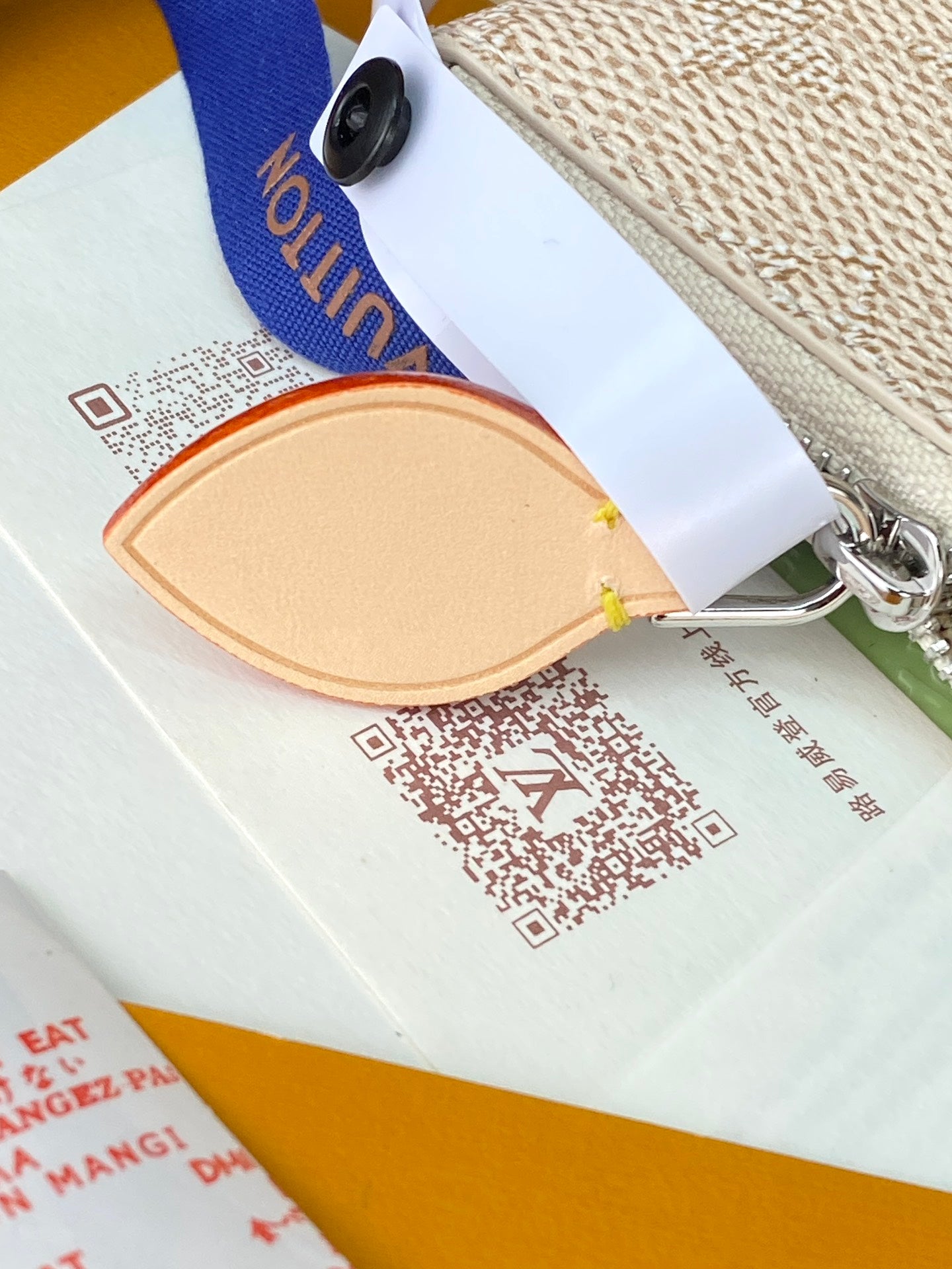 Louis Vuitton clutch strap detail with silver ring hardware and product card