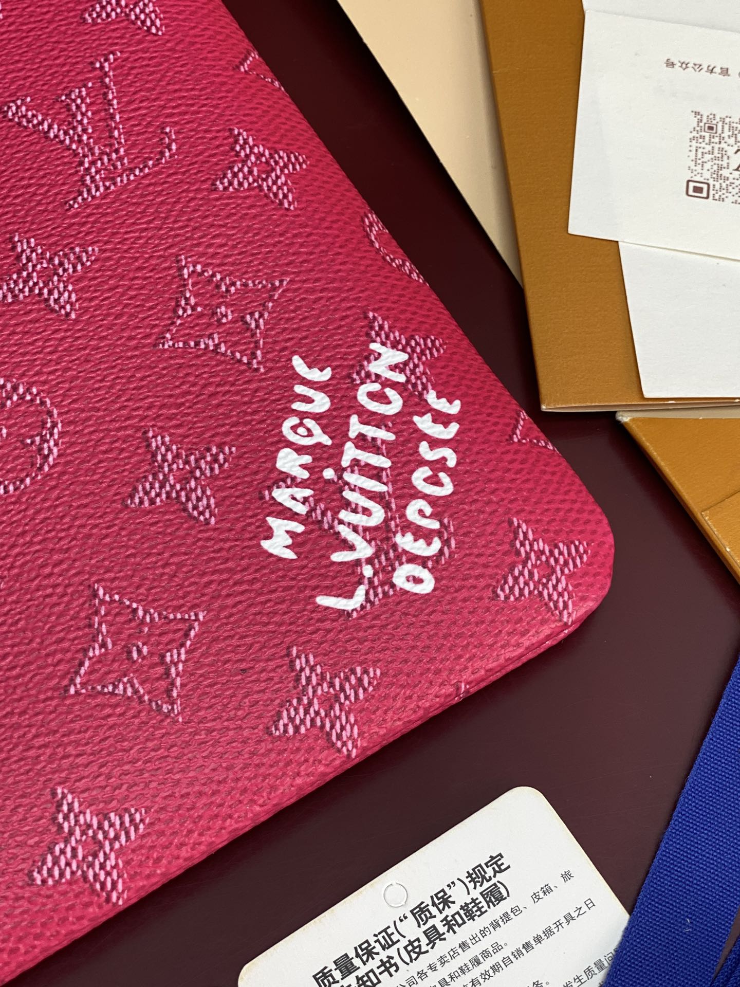 Close-up of pink Louis Vuitton monogram pouch with stylized printed lettering