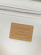 Cream leather patch label inside zipper opening with stitched border and engraved text.