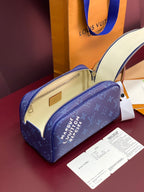 Blue monogram bag with open top, cream interior, and gold-tone zipper pull.
