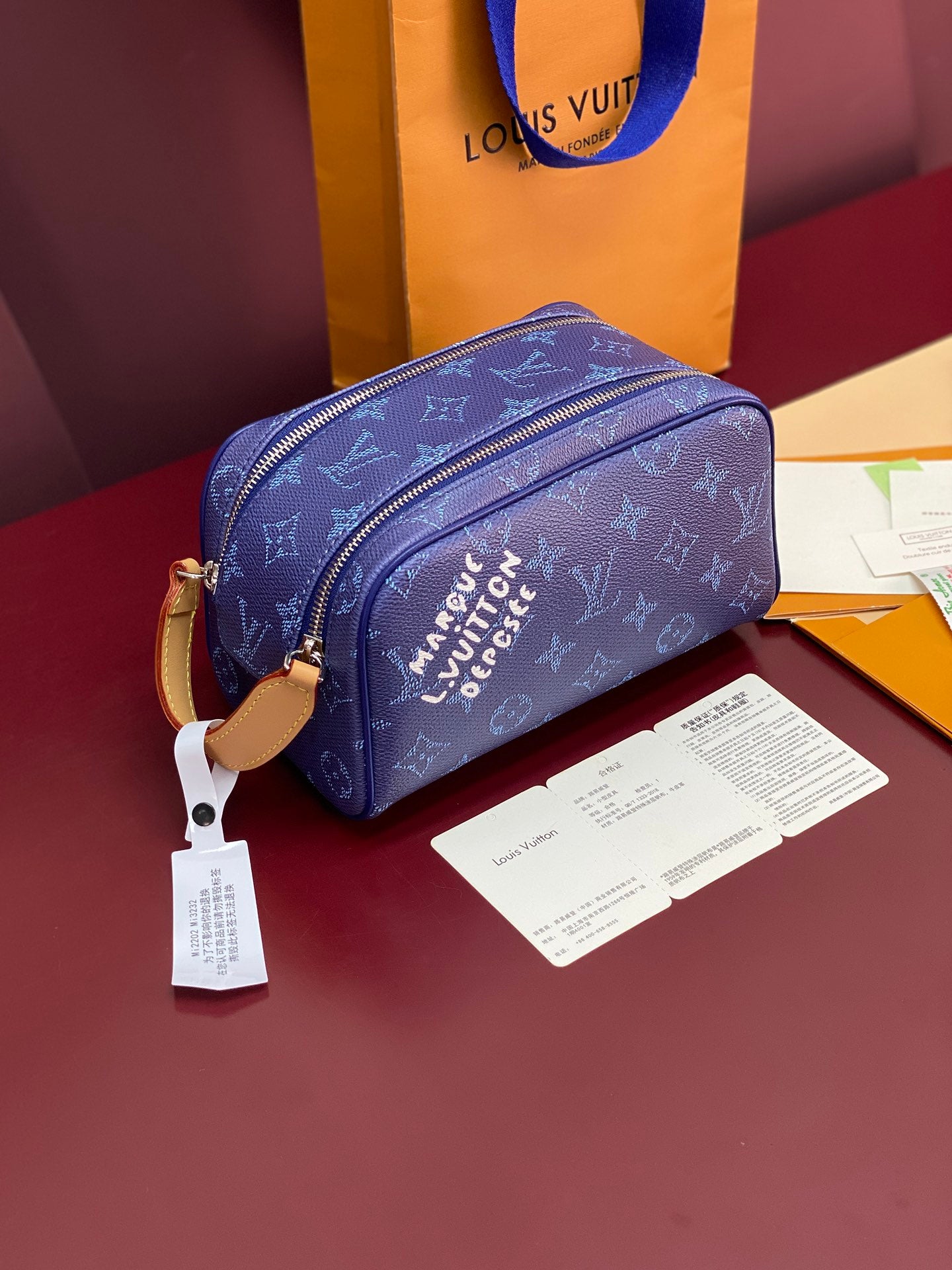 Blue monogram crossbody bag with top zip and gold-tone hardware; includes tag.