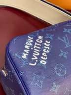 Blue monogram bag side close-up with embossed lettering and gold-tone zipper trim.