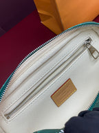 Beige interior of green monogram bag with zip track and leather patch.