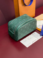 Green monogram vanity bag with curved silhouette and zip closure.