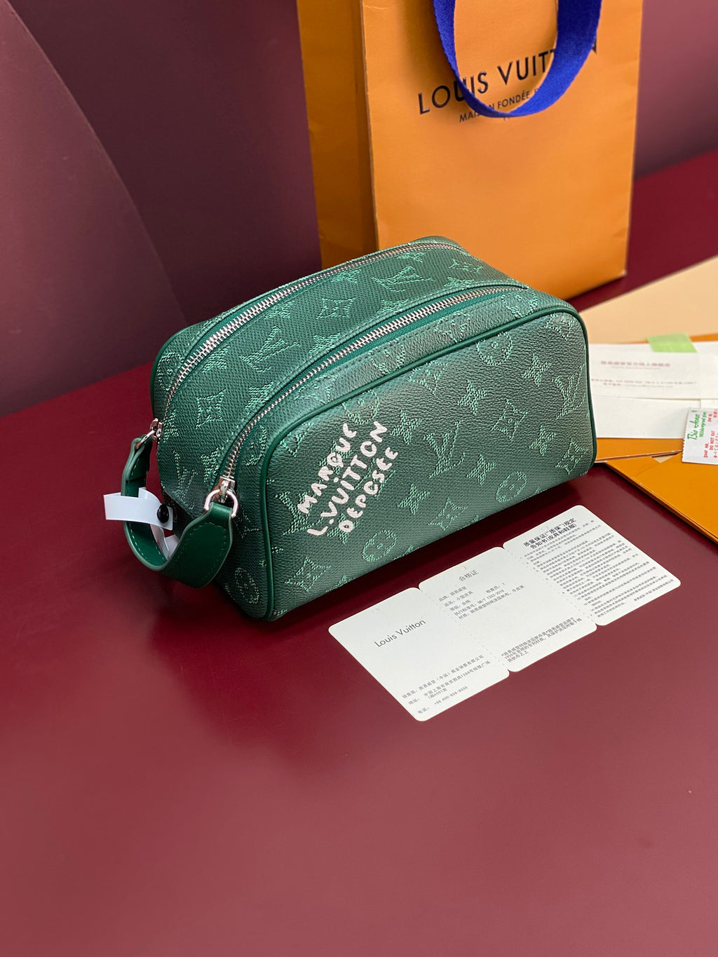 Green monogram toiletry bag with zip top and silver-tone hardware.