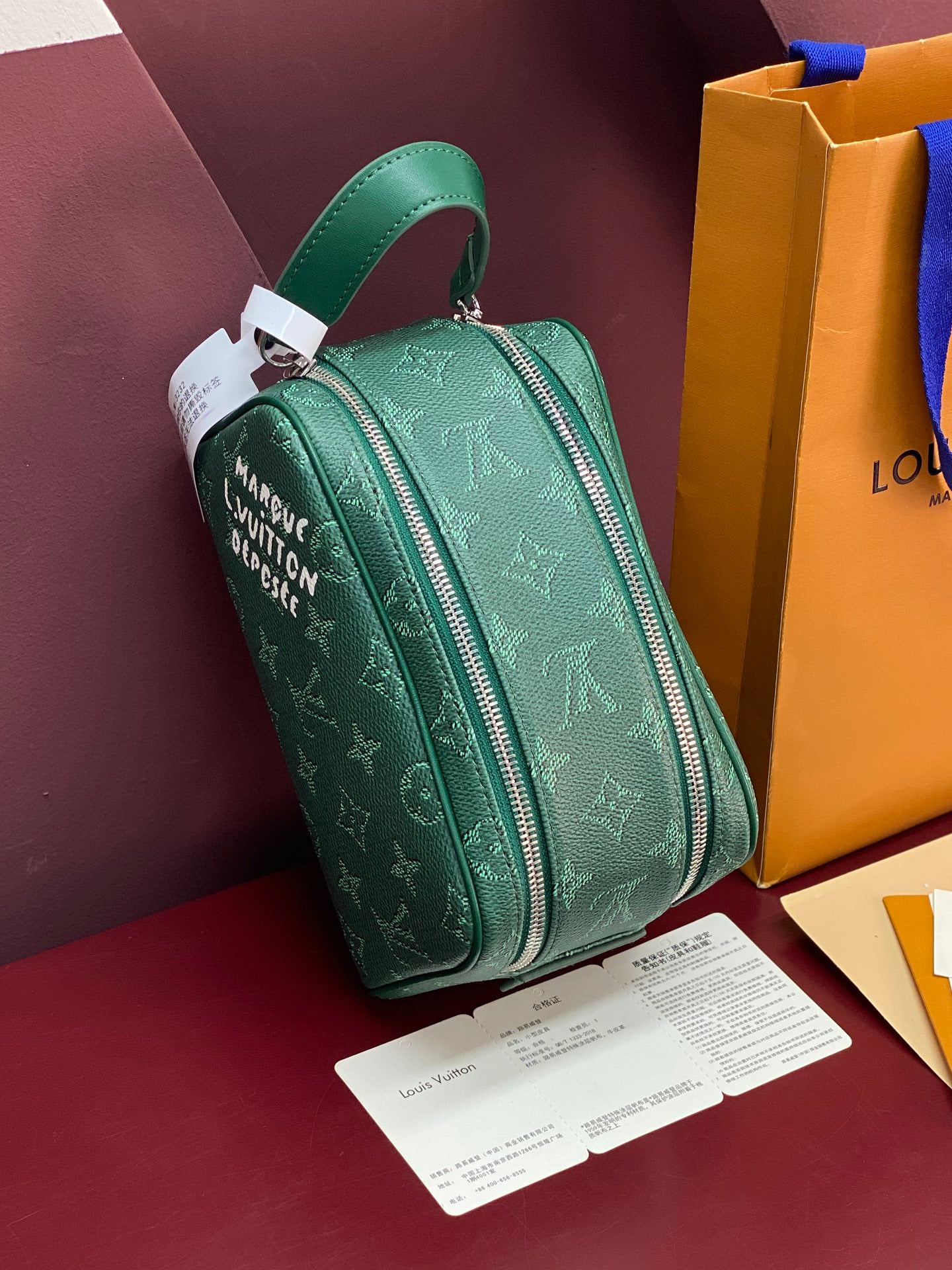 Green monogram mini crossbody bag with top zipper and leather strap.