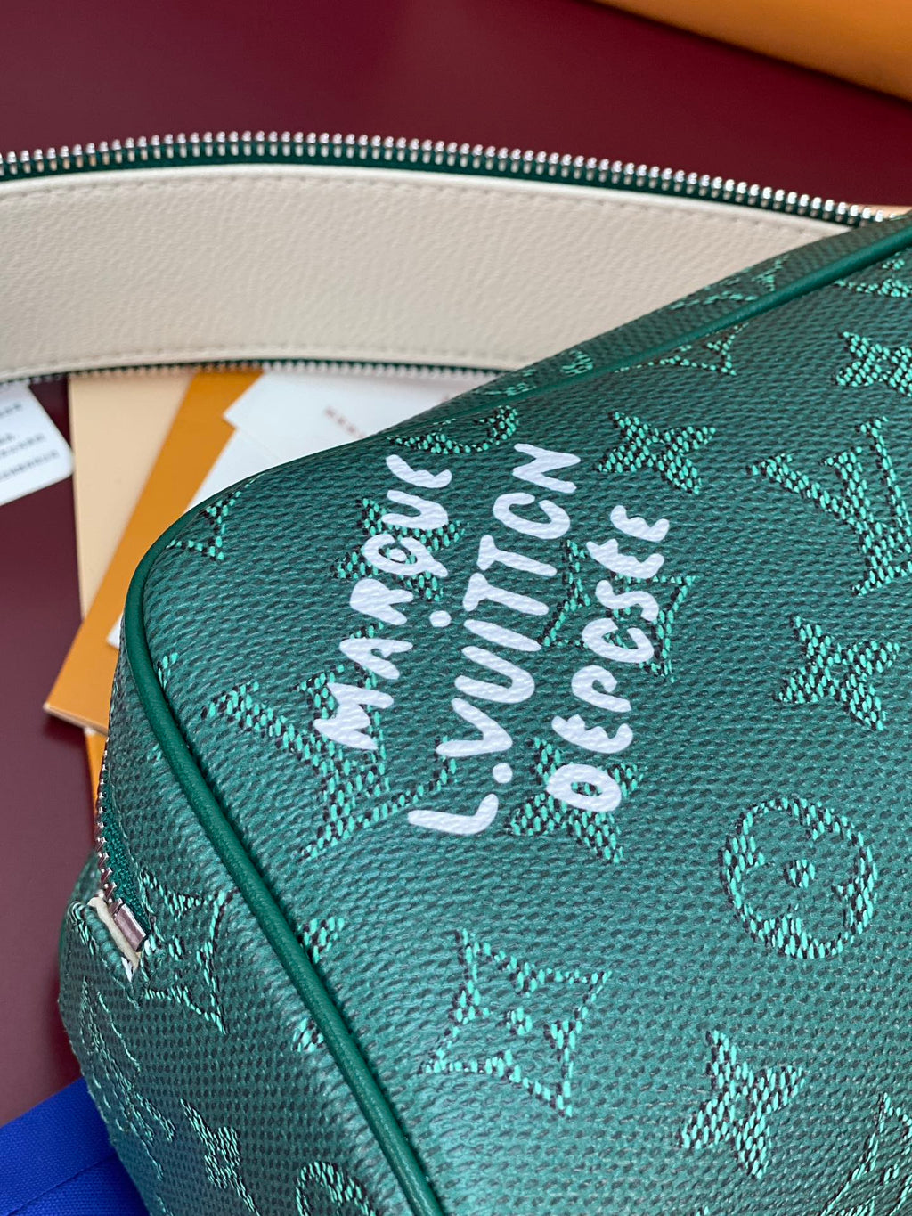 Green monogram vanity bag exterior with embossed “LOUIS VUITTON” text.