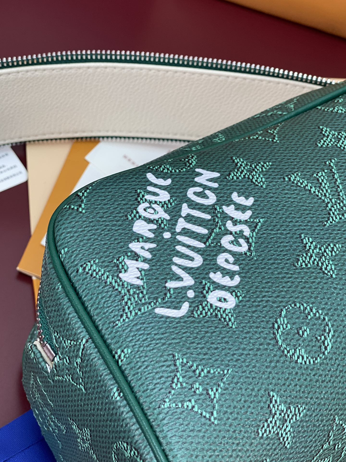 Green monogram vanity bag exterior with embossed “LOUIS VUITTON” text.