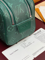 Green monogram bag corner with front leather logo patch and zipper teeth.